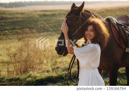 Woman in white dress is with horse on the countryside field Woman in white dress is with horse on the countryside field 139166764