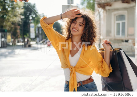 Tired, kind of. Happy woman is with shopping bags in town Tired, kind of. Happy woman is with shopping bags in town 139166863