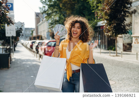 Money to spend. Happy woman is with shopping bags in town Money to spend. Happy woman is with shopping bags in town 139166921