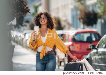 Fresh drink in paper cup. Happy woman is with shopping bags in town 139166982