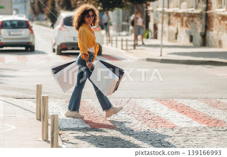 Crossing the road. Happy woman is with shopping bags in town 139166993