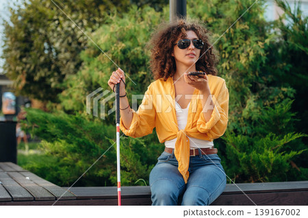 Talking by phone. A blind woman is in the modern city at daytime Talking by phone. A blind woman is in the modern city at daytime 139167002