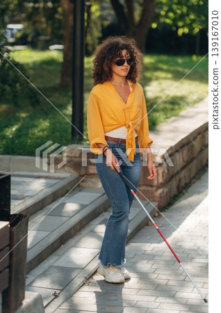 By the help of white cane. A blind woman is in the modern city at daytime 139167010