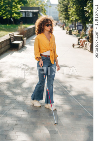 By the help of white cane. A blind woman is in the modern city at daytime By the help of white cane. A blind woman is in the modern city at daytime 139167011