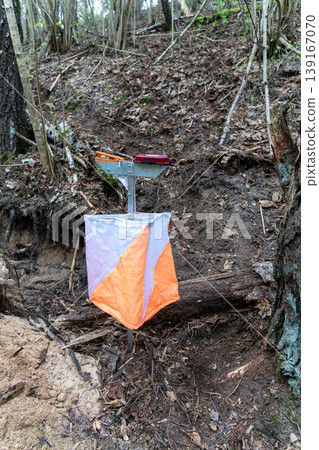 Orienteering control point with orange and white flag 139167070