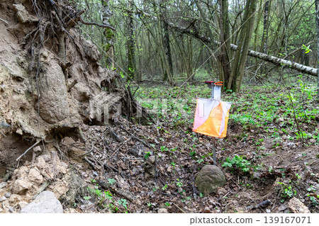 Orienteering control point with orange and white flag 139167071