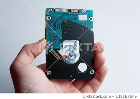 A hand holds hard disk drive against the white background 139167679