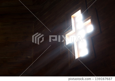 Light goes into a wooden church through the cross-shaped window  139167687