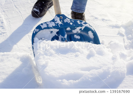 Young man cleaning narrow path in front of the private house in the suburb. Shoveling snow after a heavy snowfall in the sunny winter morning Young man cleaning narrow path in front of the private house in the suburb. Shoveling snow after a heavy snowfall in the sunny winter morning 139167690