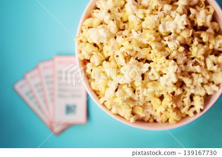 Fresh tasty unhealthy popcorn in big bucket, movie tickets laying near on table Fresh tasty unhealthy popcorn in big bucket, movie tickets laying near on table 139167730