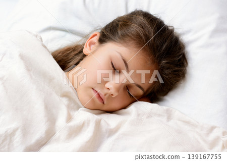 Beautiful young girl sleeping on comfortable warm bed after having games and playing with toys. Little girl has good sleep after hard day of studying. Concept of having good sleep at night Beautiful young girl sleeping on comfortable warm bed after having games and playing with toys. Little girl has good sleep after hard day of studying. Concept of having good sleep at night 139167755