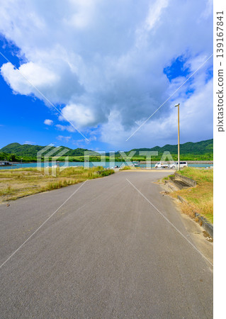 The tranquil scenery of Funakoshi Fishing Port on Ishigaki Island, surrounded by blue skies and mountain ranges. The tranquil scenery of Funakoshi Fishing Port on Ishigaki Island, surrounded by blue skies and mountain ranges. 139167841