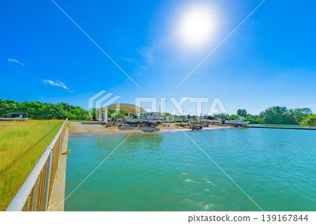 Ishigaki Island: A tropical harbor scene of Funakoshi Fishing Port shining under a blue sky. Ishigaki Island: A tropical harbor scene of Funakoshi Fishing Port shining under a blue sky. 139167844
