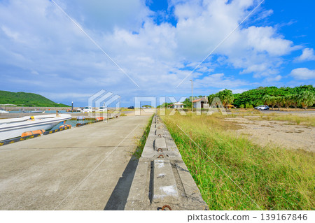 Ishigaki Island: A tranquil scene of the quay at Funakoshi Fishing Port, with a clear blue sky and clouds. Ishigaki Island: A tranquil scene of the quay at Funakoshi Fishing Port, with a clear blue sky and clouds. 139167846