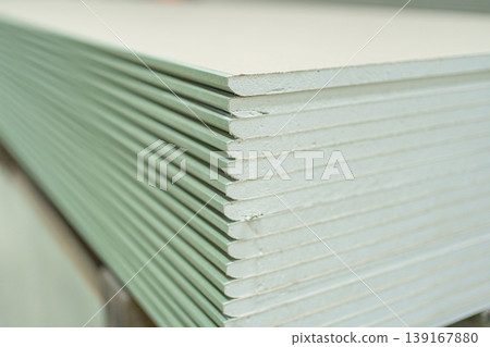 Gypsum plasterboard panels arranged in a neat stack. Detailed view of construction material widely used for partitions, ceilings and interior design projects. Gypsum plasterboard panels arranged in a neat stack. Detailed view of construction material widely used for partitions, ceilings and interior design projects. 139167880