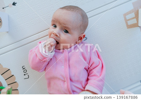 Close-up of three month old baby sucking fist. Self soothing behavior, teething and early development concept. Infant calming by sucking hand. Natural reflex, comfort and sensory development. Close-up of three month old baby sucking fist. Self soothing behavior, teething and early development concept. Infant calming by sucking hand. Natural reflex, comfort and sensory development. 139167886