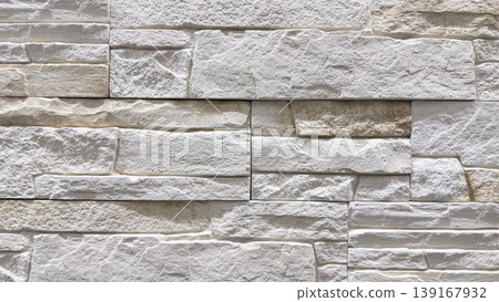 Close-up of white decorative stone wall texture with layered masonry pattern and rough surface 139167932