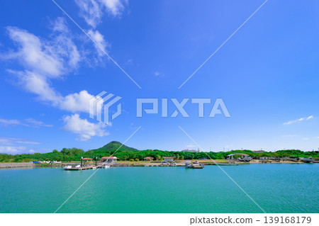 Ishigaki Island: The beautiful scenery of Funakoshi Fishing Port with its emerald sea and mountain range. 139168179