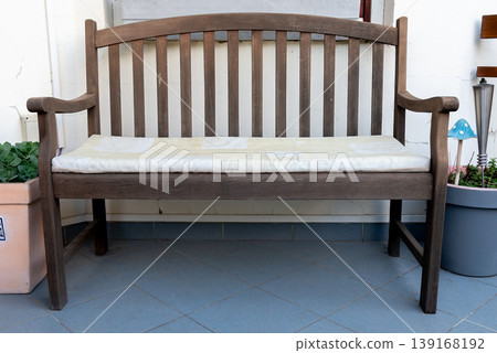 A wooden bench with a seat cushion with potted plants on both sides. A wooden bench with a seat cushion with potted plants on both sides. 139168192