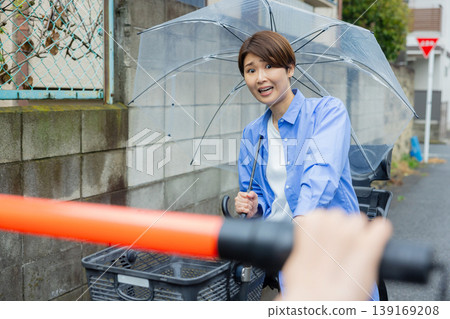 一名女子騎著腳踏車,手裡拿著一把傘。 一名女子騎著腳踏車,手裡拿著一把傘。 139169208