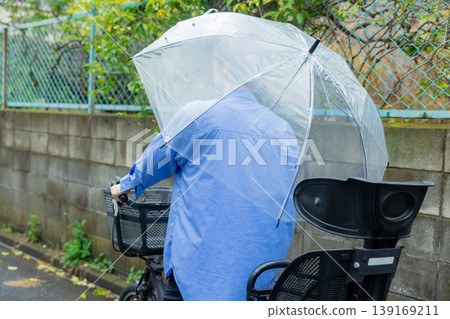 A woman riding a bicycle while holding an umbrella. 139169211