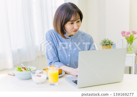 中年婦女邊工作邊吃早餐 中年婦女邊工作邊吃早餐 139169277
