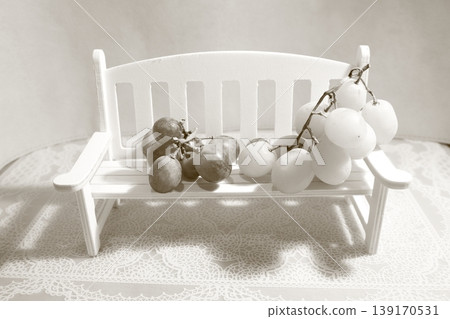 Miniatures on a white chair and red and white grapes Miniatures on a white chair and red and white grapes 139170531