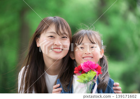 母親節這天,一對母女面帶微笑,手捧康乃馨,在綠意盎然的背景下對著鏡頭說:“媽媽,謝謝你的一切!” 母親節這天,一對母女面帶微笑,手捧康乃馨,在綠意盎然的背景下對著鏡頭說:“媽媽,謝謝你的一切!” 139171602