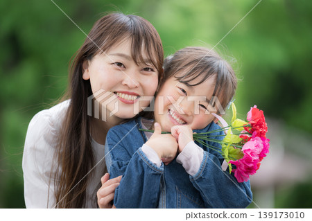 A mother and daughter smiling and looking at the camera with carnations against a backdrop of fresh greenery on Mother's Day, with the message "Thank you for everything, Mom!" A mother and daughter smiling and looking at the camera with carnations against a backdrop of fresh greenery on Mother's Day, with the message "Thank you for everything, Mom!" 139173010