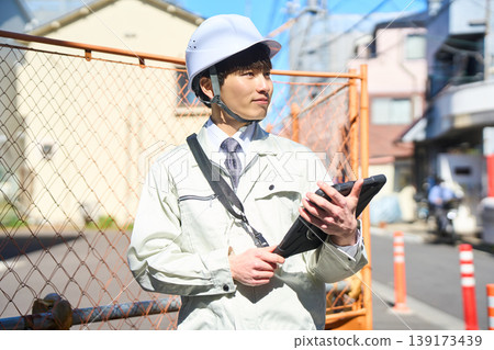 一名男性工地主管正拿著平板電腦查看施工現場的狀況。 139173439