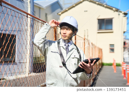 一名男性工地主管正拿著平板電腦查看施工現場的狀況。 一名男性工地主管正拿著平板電腦查看施工現場的狀況。 139173451