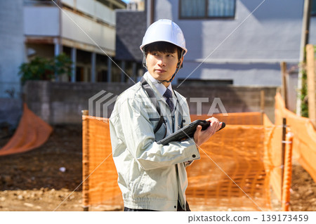 A male site supervisor is holding a tablet to check the status of the construction site. A male site supervisor is holding a tablet to check the status of the construction site. 139173459