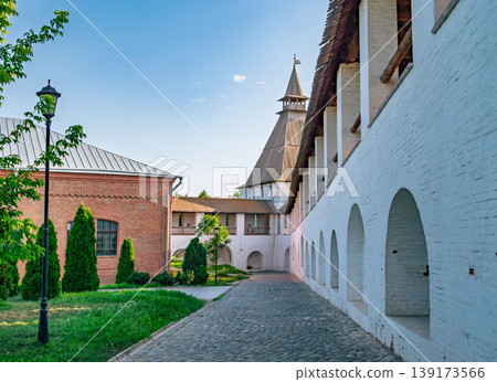 Astrakhan Kremlin inner grounds in Russia displaying historical white walls, cobblestone path, and a towering structure on a clear day 139173566