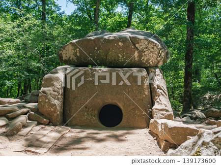 Prehistoric megalithic tomb made of massive stone blocks hidden deep within a vibrant summer forest Prehistoric megalithic tomb made of massive stone blocks hidden deep within a vibrant summer forest 139173600