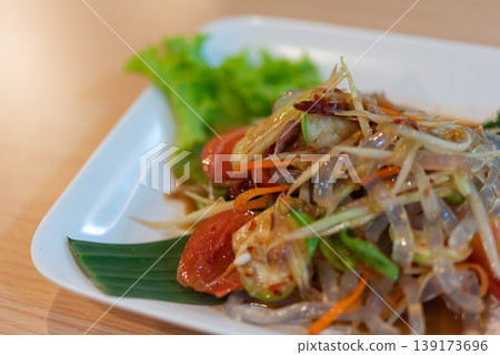 Close up Thai glass noodle papaya salad with spicy dressing fresh vegetables tomato chili and herbs on plate vibrant healthy cuisine and natural light Close up Thai glass noodle papaya salad with spicy dressing fresh vegetables tomato chili and herbs on plate vibrant healthy cuisine and natural light 139173696