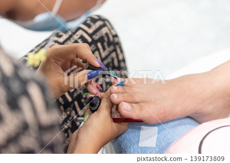 Close up of pedicure session with technician applying nail polish on client toes showing beauty care hygiene relaxation and professional salon service Close up of pedicure session with technician applying nail polish on client toes showing beauty care hygiene relaxation and professional salon service 139173809