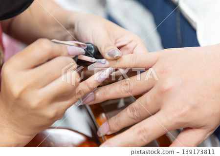 Close up of manicure session with technician applying gel polish on fingernails showing beauty care hygiene precision and professional salon service for healthy stylish hands 139173811
