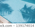 Amazing summer abstract background palm leaf shadows on calm swimming pool water sunshine tropical travel vacation wallpaper design serene ripple texture sunlight aesthetic leisure concept 139174014