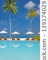 Tranquil reflection of luxury resort pool sunbeds umbrellas and palm trees summer travel background perfect tropical tourism scenery elegant poolside lounge area premium vacation atmosphere 139174029