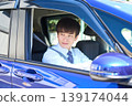 A young Japanese businessman smiles as he looks out the window from the driver's seat of his company car. 139174044