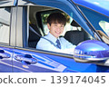 A young Japanese businessman smiles as he looks out the window from the driver's seat of his company car. 139174045