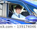 A young Japanese businessman smiles as he looks out the window from the driver's seat of his company car. 139174046