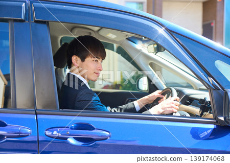 一位身穿西裝的日本商人坐在汽車駕駛座上,面向前方,專心致志地安全駕駛。 一位身穿西裝的日本商人坐在汽車駕駛座上,面向前方,專心致志地安全駕駛。 139174068