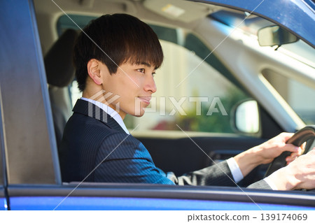 一位身穿西裝的日本商人坐在汽車駕駛座上,面向前方,專心致志地安全駕駛。 一位身穿西裝的日本商人坐在汽車駕駛座上,面向前方,專心致志地安全駕駛。 139174069