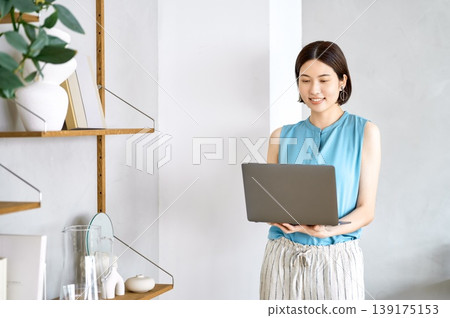 A Japanese woman's smiling lifestyle working from home on her laptop. 139175153