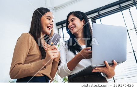 Two women smile together, one holding a credit card 139175426