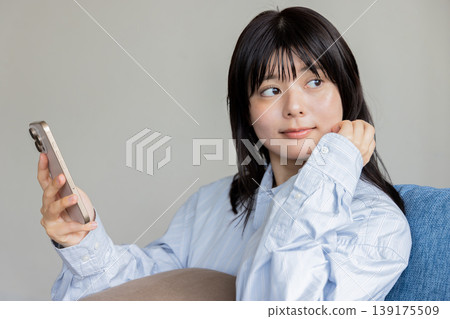 坐長沙發和操作智能手機的婦女 139175509
