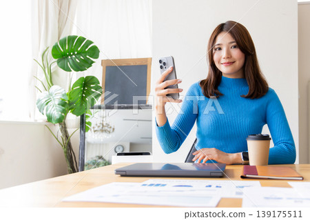 拿著智能手機的一名微笑的婦女 拿著智能手機的一名微笑的婦女 139175511
