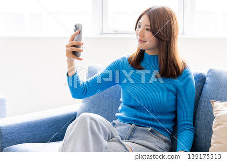 A woman watching a smartphone A woman watching a smartphone 139175513