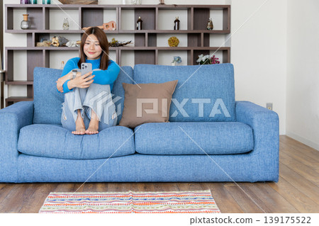 Woman looking at smartphone in the room Woman looking at smartphone in the room 139175522